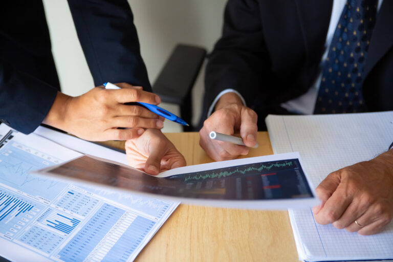 Investor and broker discussing trading strategy, holding papers with financial charts and pens. Cropped shot. Broker job or investment concept